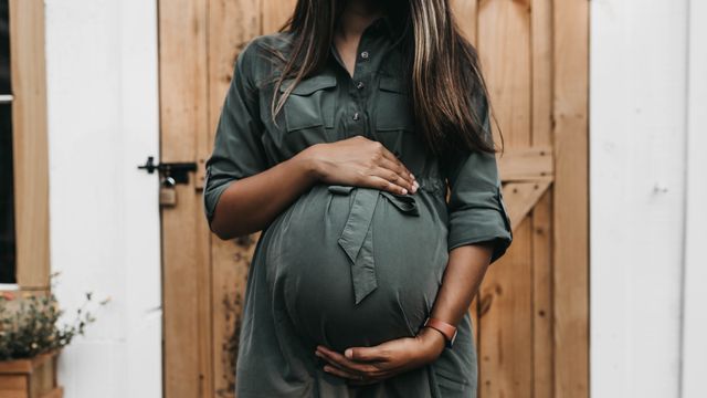 A pregnant woman cradling her bump. 