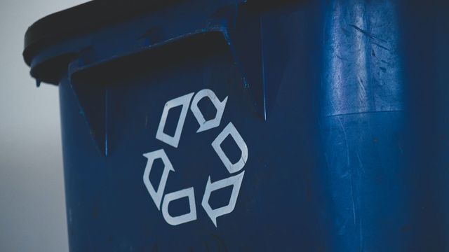 A blue bin with a recycling symbol on it. 