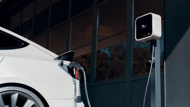 A white electric car plugged into a charging station. 