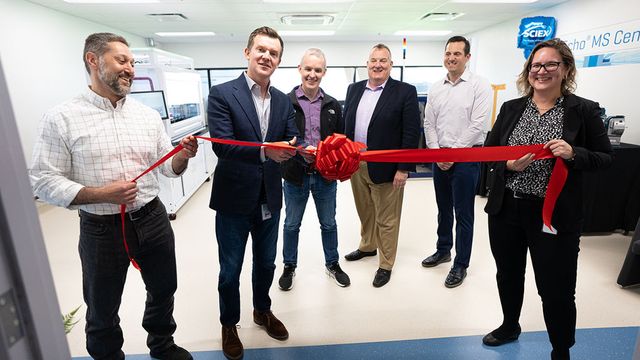 Scientists at the opening of the new MS center cutting a red ribbon. 