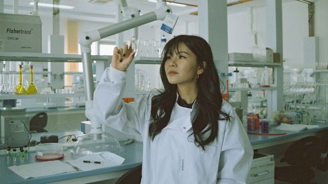 A scientist holding up a glass vial. 