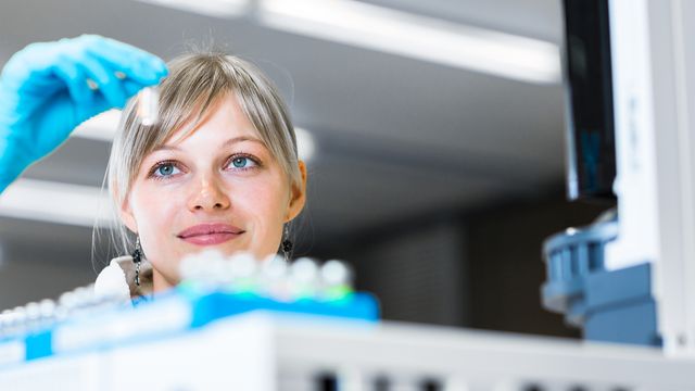 A scientist holding up a vial.  