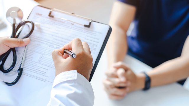 A doctor holding a clipboard with a patient. 