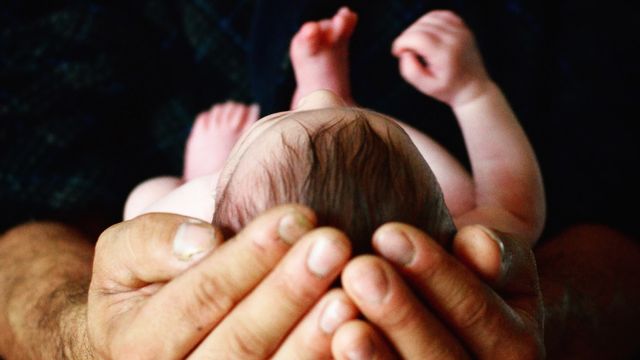 A man holds a baby in his hands.  