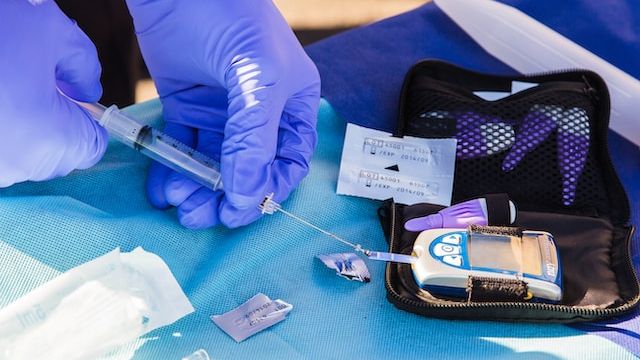 A person adding a blood sample to a testing strip on a glucose monitor. 