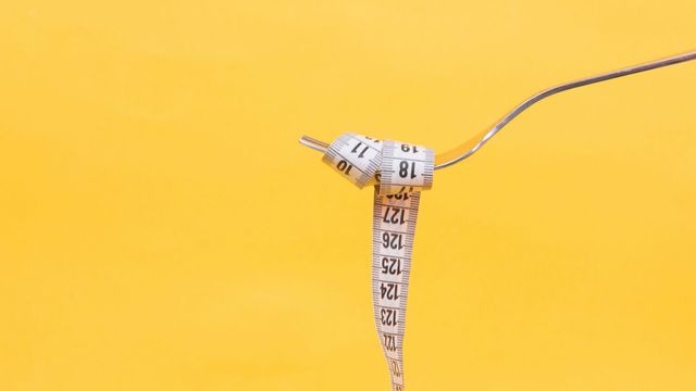 A measuring tape wrapped around a fork. 