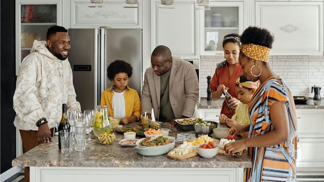 A family prepares food in a kitchen. 